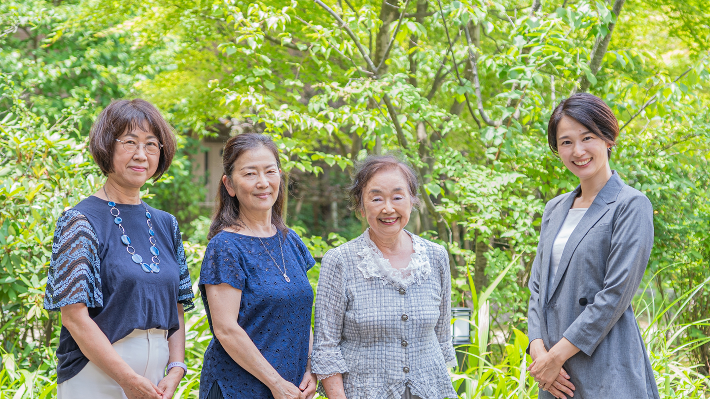 ホワイトホースシアタージャパンの旧体制の女性3人と新体制女性1人、合計4人の記念写真です。草木を背景に4人が横並びで、カメラの方を見ています。